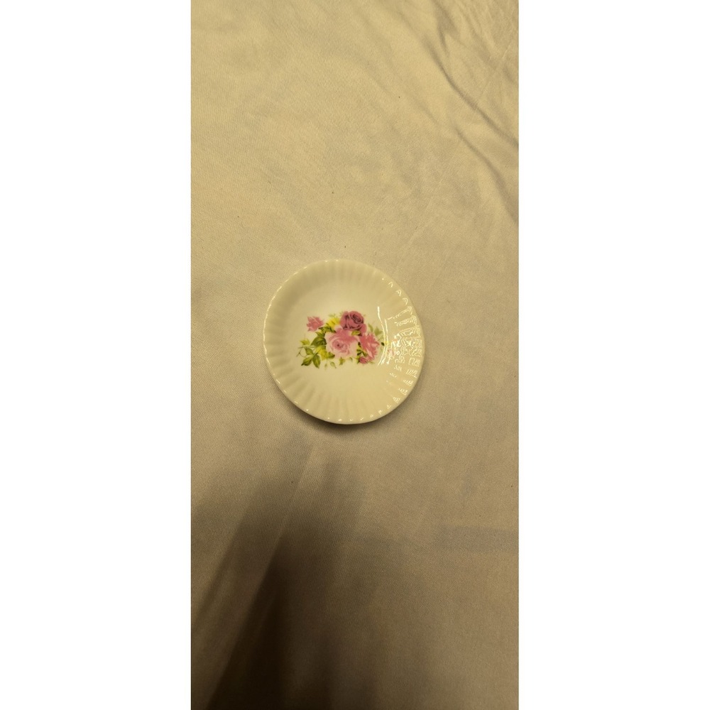 porcelain saucer featuring a pink floral design and a scalloped edge